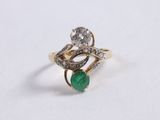a close up of a diamond and emerald ring on a white surface