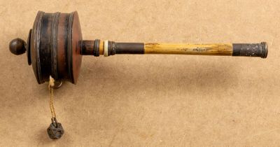 un vieux rouet en bois muni d'une poignée en bois, posé sur une surface marron