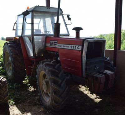 a red tractor that is parked in the shade