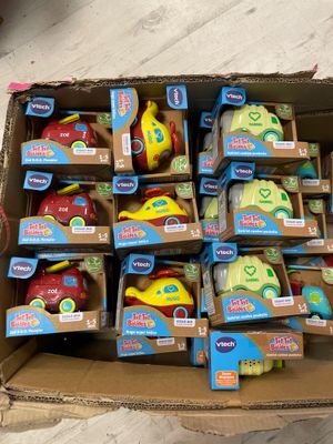 une boîte en carton remplie de jouets, posée par terre et mise en vente
