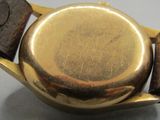 a close up of a gold watch with a brown leather band