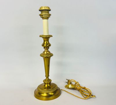 a brass plated candle holder with a white candle on top of it