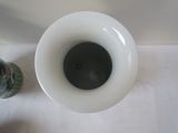a white vase with a black lid next to a can of soda