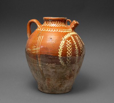 brown and white vase with designs on it on a gray surface