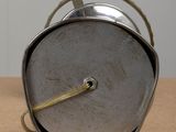 a silver clock with a rope around it sitting on a table