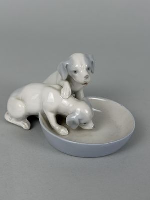 porcelain figurine of a dog and a cat sitting on a plate