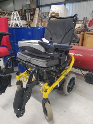 a wheelchair that is sitting in a warehouse with other chairs