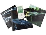 trois livres posés sur une surface blanche, avec une voiture de sport noire en arrière-plan
