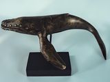 sculpture of a humpback whale on a black stand on a blue background