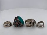three silver rings and a turquoise stone ring on a white surface