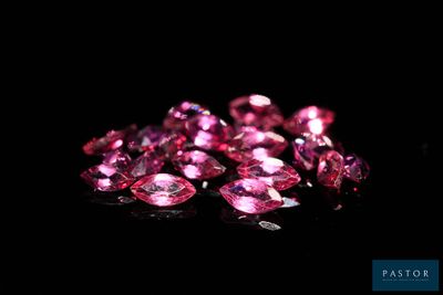 a pile of pink diamonds on a black surface