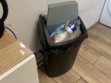 une poubelle noire posée à côté d'un lave-linge et d'un sèche-linge dans une salle de bains