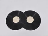 two black vinyl records sitting on top of a white surface
