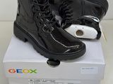 une paire de bottes noires posée sur une boîte blanche contenant un téléphone