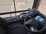 a steering wheel and control panel in the driver ' s seat of a bus