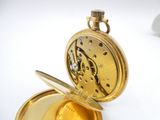 a gold pocket watch that is open on a white surface