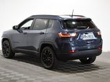 the back end of a blue jeep compass parked on a checkered floor