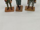 three figurines of men dressed in military uniforms