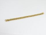 gros plan d'un bracelet en or sur une surface blanche