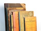 several books are stacked on top of each other on a white surface