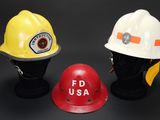 trois casques de pompiers sont alignés sur une surface noire