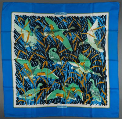 a blue square scarf with birds and grass on it