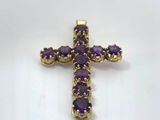 a purple cross pendant on a white surface