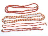 three orange and white beaded necklaces on a white surface