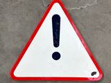 a red and white sign with a black exclamation on it