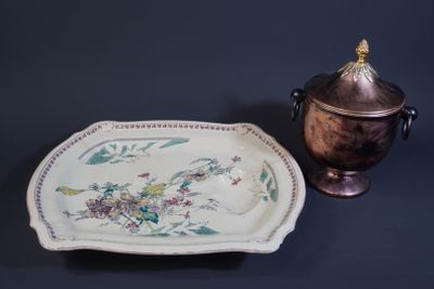a plate with a flower design on it next to a silver urn