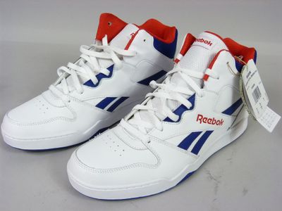 Des baskets blanches ornées de bordures bleues et rouges sont posées sur une surface blanche