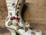 a white boot with berries on it sitting on a wooden table