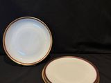 two plates with gold rims are sitting on a black cloth