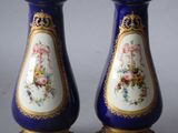 pair of blue and gold vases with flowers on them on a gray surface