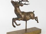 sculpture en bronze représentant un cerf au galop, posée sur un socle en bois