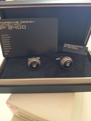 deux boutons de manchette en argent dans une boîte posée sur une table blanche