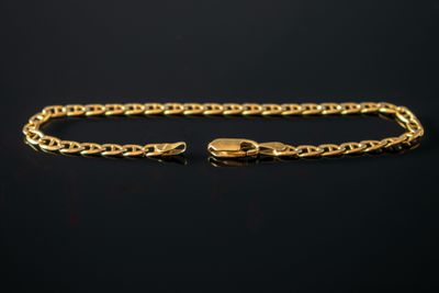 un bracelet à chaîne en or avec un fermoir sur fond noir