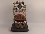 une petite chaise décorative sur laquelle est posé un coussin rouge