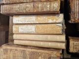 several old books are stacked on top of each other on a shelf