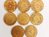 six types différents de pièces d'or disposées sur une surface blanche