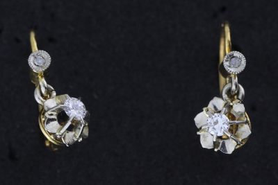 une paire de boucles d'oreilles en diamant et en or posées sur une surface noire