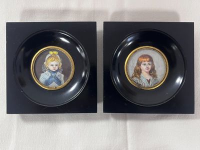 two black plates with pictures of a girl and a boy on them