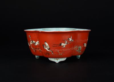 un bol rouge orné d'oiseaux et de fleurs sur un fond noir