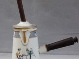 une cafetière blanche avec une poignée en bois posée sur une table