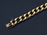 a close up of a gold chain bracelet on a black surface