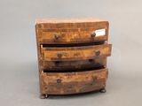 a small wooden chest of drawers with a label on it