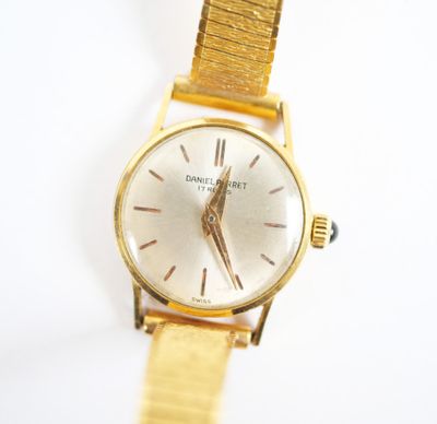 gros plan d'une montre en or sur une surface blanche