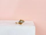 un gros plan d'une bague en or et diamants posée sur un bloc de marbre