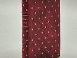 un vieux livre à la couverture rouge ornée de clous dorés