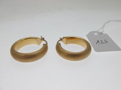 une paire de boucles d'oreilles en or sur fond blanc